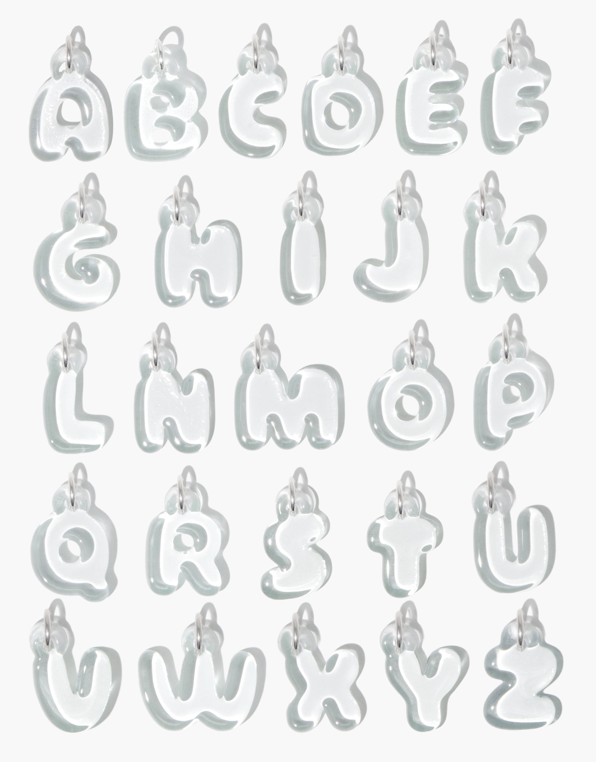 Transparent bubble-style alphabet letter charms arranged in rows, showcasing A to Z. Each charm features a rounded, inflated appearance with a small loop for attachment. Letter Charm | Alphabet product by CLED