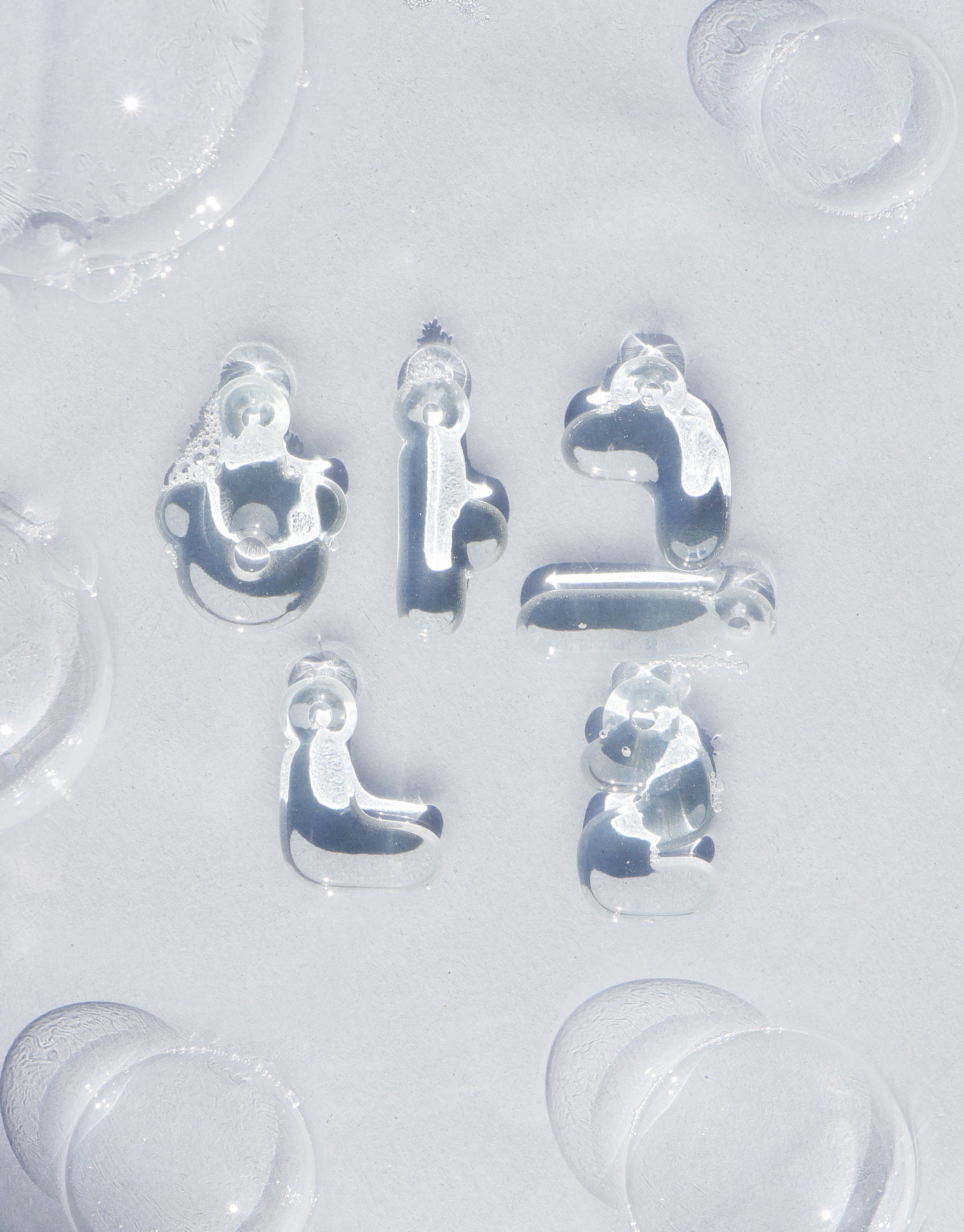 Transparent glass Hangul letter charms arranged on a light background, showcasing the unique bubble-like design of Korean alphabet characters. Eco-friendly jewelry celebrating language and culture. Letter Charm | 한글 Hangul by CLED