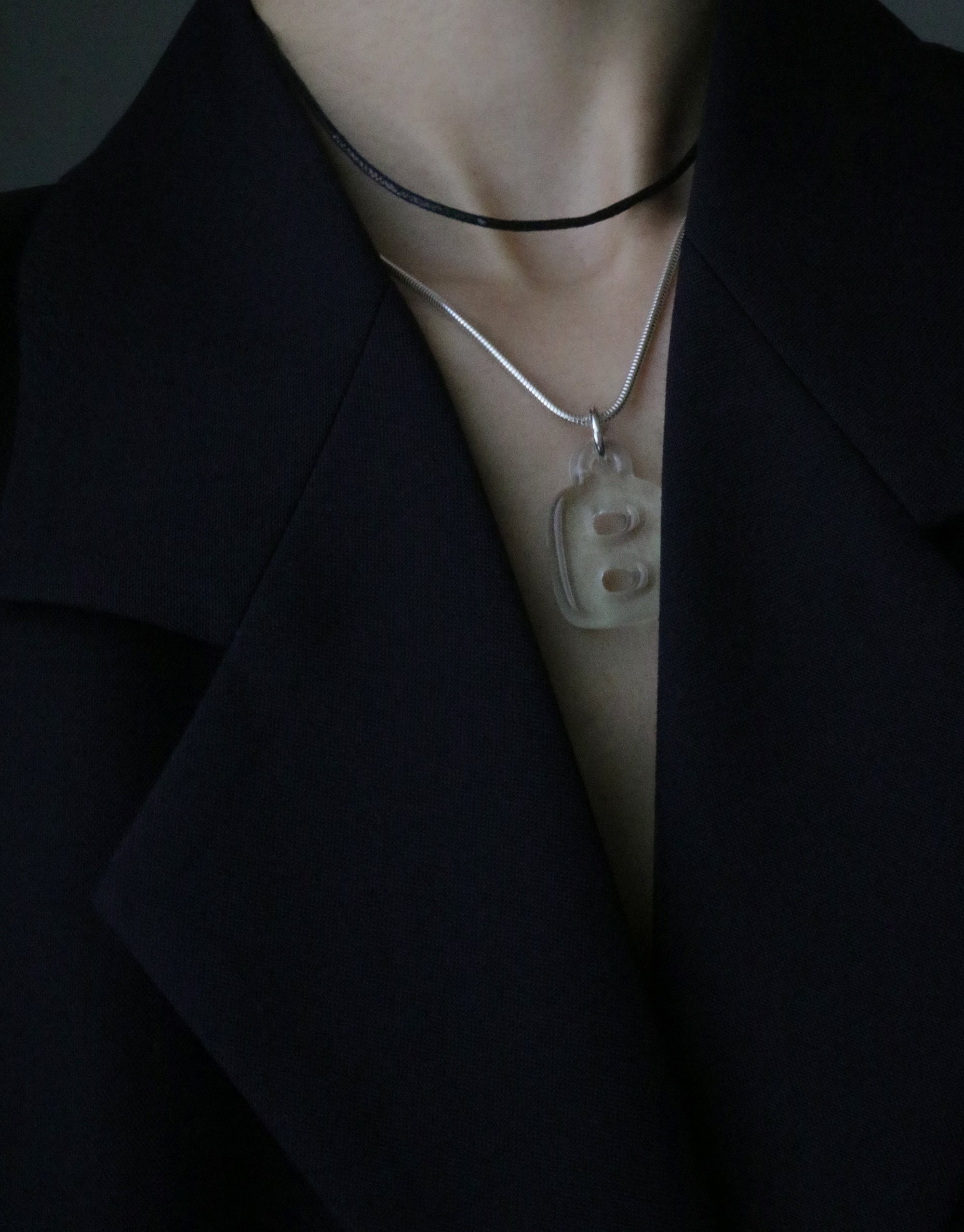 Close-up of Snake Chain Necklace worn with a letter B pendant, showcasing its versatile styling against a black lapel. Adjustable length for perfect fit, ideal for pairing with various charms. Elegant accessory for any outfit. Snake Chain Necklace by CLED.