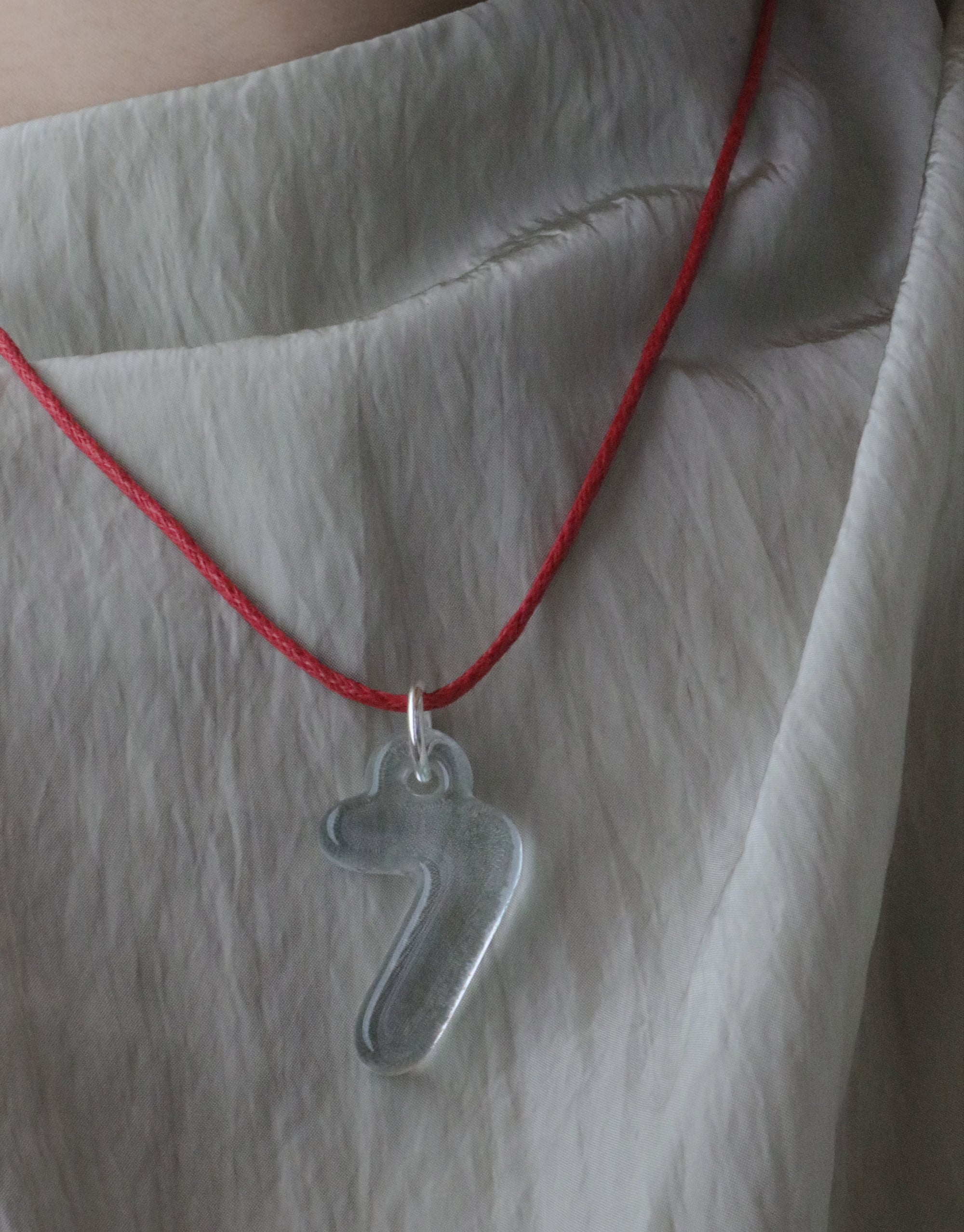 Transparent bubble-shaped number 7 charm pendant on red cord necklace, showcasing eco-friendly design made from recycled window glass. Stylish and sustainable Number Charm accessory for personal expression. CLED