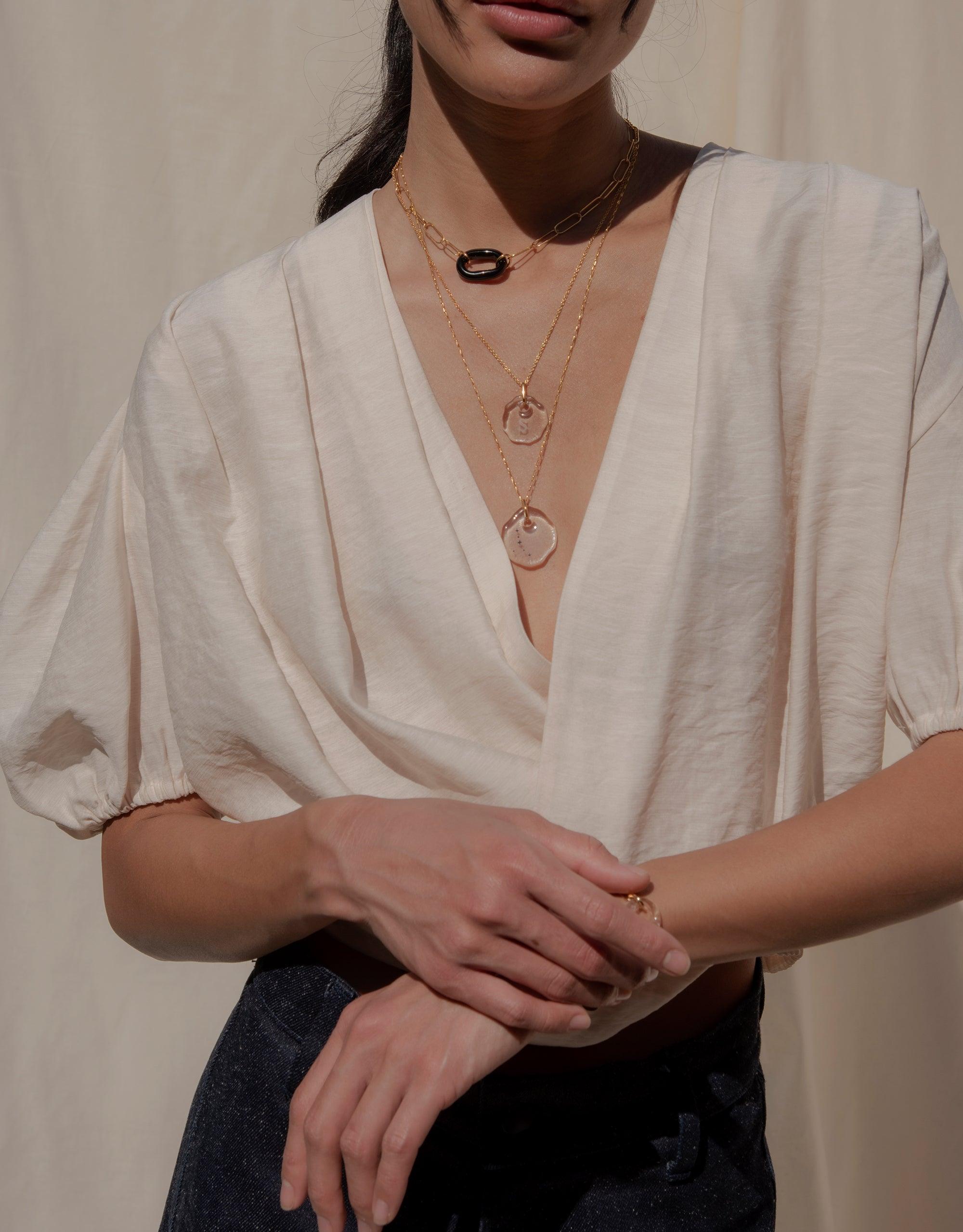 The Day Loop Necklace elegantly drapes around a woman's neck, featuring an oval chain and minimal loop design, embodying CLED's eco-conscious craftsmanship from repurposed glass.