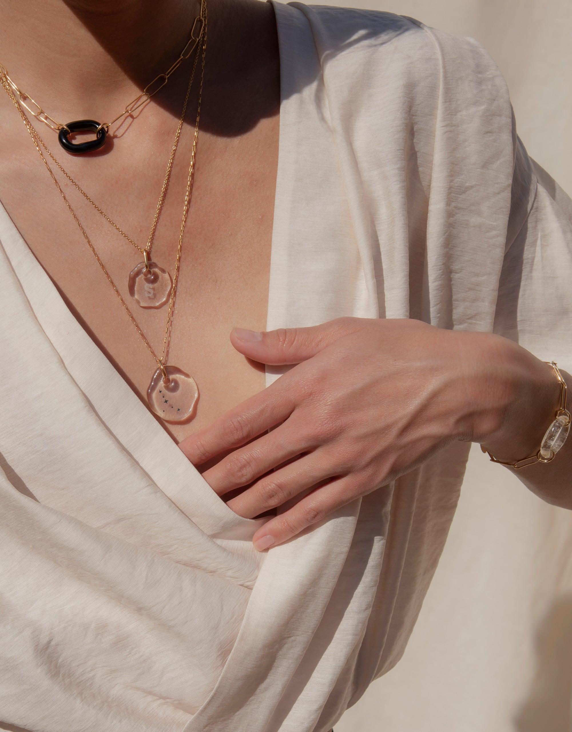 The Day Loop Necklace features a minimal oval chain with a hand-formed Eco Gem, showcased on a person, highlighting its elegant simplicity and eco-conscious craftsmanship from repurposed glass.